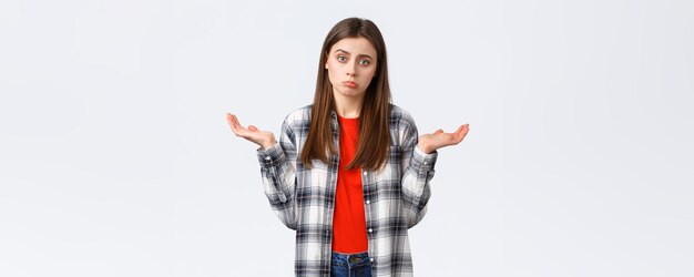Lifestyle different emotions leisure activities concept Reluctant and careless young woman shrugging with hands spread sideways dont know cant help have no idea stand white background