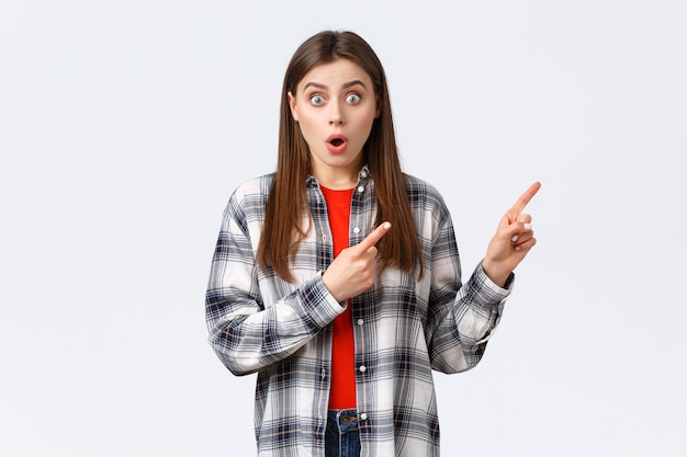 Lifestyle, different emotions, leisure activities concept. Wow amazing look here. Astonished young speechless girl showing cool new promo, pointing fingers upper right corner and stare camera.