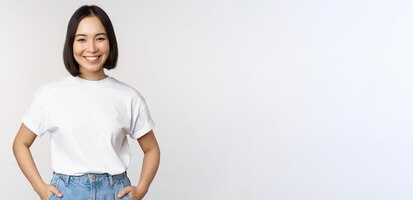 Lifestyle happy modern asian girl smiling and looking happy at camera posing in white tshirt and jeans studio background