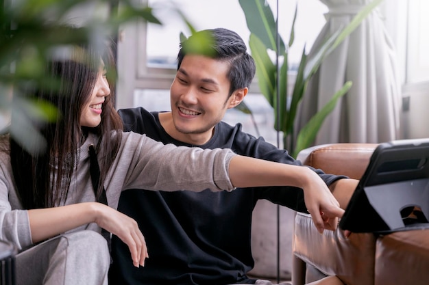 Образ жизни дома азиатская женщина остается дома вместе со своим мужем смотрит фильм онлайн на планшете на диване в гостиной домашняя азиатская семейная пара проводит выходные вместе дома