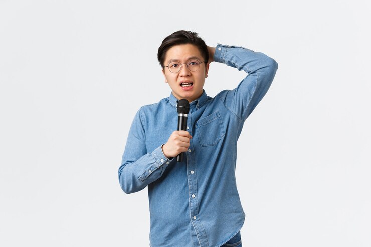 無料Photo ライフスタイル、レジャー、人々のコンセプト。恥ずかしがり屋で不安なアジア人の男がマイクを使って白い背景の上に優柔不断に立って、人前でスピーチをするのが怖くて、不安な白い背景に立っています。