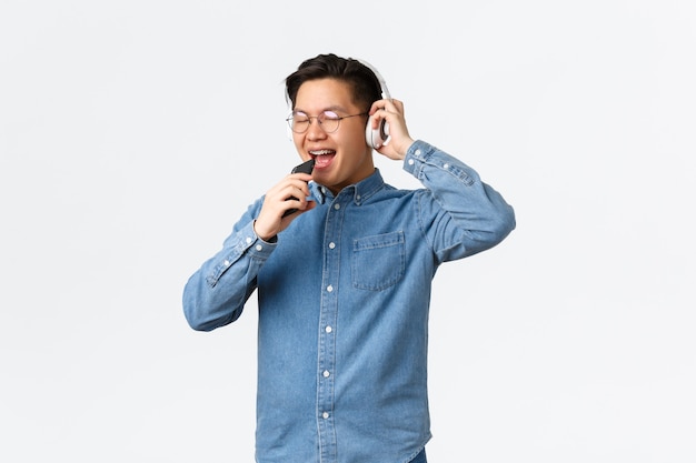 라이프스타일 레저 및 기술 개념 근심 없는 행복한 아시아 청년이 Wi-Fi를 사용하여 노래방 앱을 재생합니다.