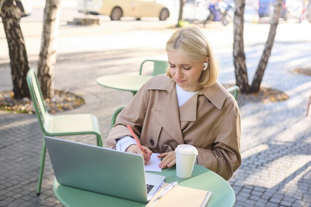 Free photo lifestyle and people concept woman in outdoor cafe sitting with laptop on street connects to online