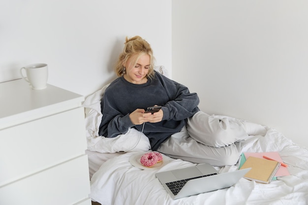 Foto gratuita lo stile di vita e le persone concetto giovane bella donna che rimane a casa sdraiato a letto con il laptop e