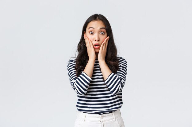 Lifestyle, people emotions and casual concept. Surprised gasping woman stare impressed, losing speech from emotions, drop jaw and touch face amazed, standing white background
