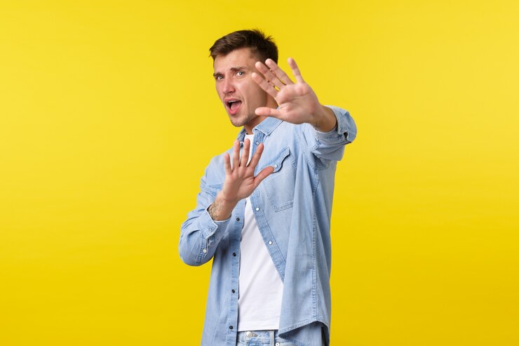 Free Photo lifestyle, people emotions and summer leisure concept. scared insecure blond guy trying avoid conflict, asking please stop, defending himself with raised hands, standing yellow background.