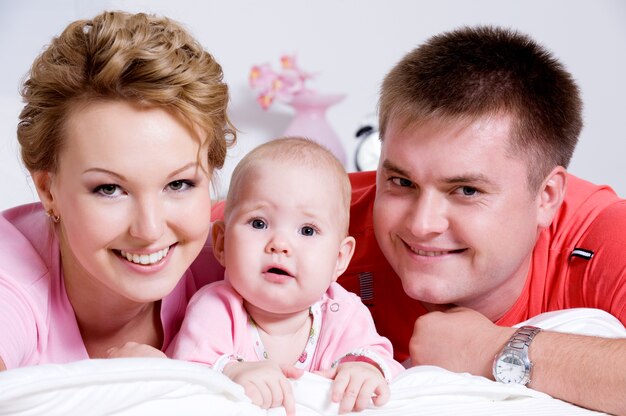 Портрет образа жизни красивой молодой счастливой семьи, лежа в постели у себя дома