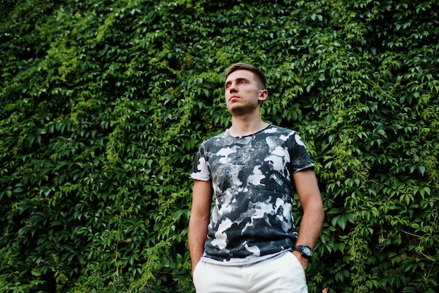 Lifestyle portrait of handsome man posing against greenery wall