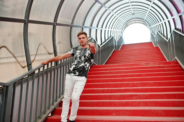 Образ жизни портрет красивого мужчины, позирующего на красной лестнице городского тоннеля