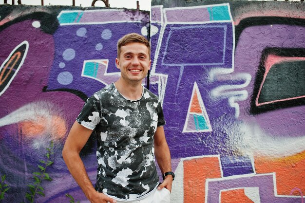 Образ жизни портрет красивого мужчины, позирующего на улице города со стеной граффити