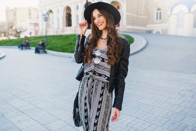 Lifestyle portrait of pretty cheerful woman enjoying holidays in old European city. Street fashion look.  Stylish spring outfit.