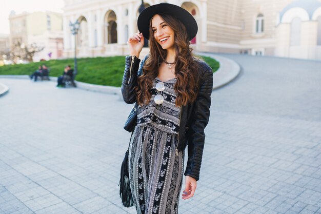 Lifestyle portrait of pretty cheerful woman enjoying holidays in old European city. Street fashion look.  Stylish spring outfit.