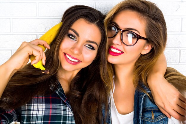 Lifestyle portrait of two pretty teen girlfriends smiling hugs and having fun