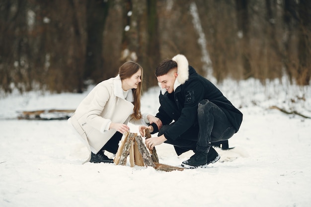 雪に覆われた森のカップルのライフスタイルショット。冬休みを屋外で過ごす人々。焚き火のそばの人々。