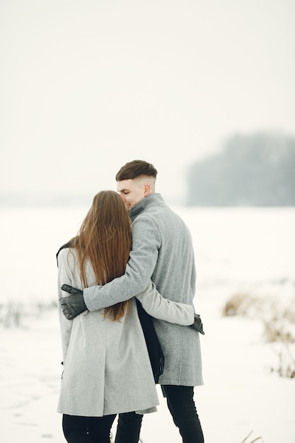 雪の森を歩くカップルのライフスタイルショット。冬休みを屋外で過ごす人々。