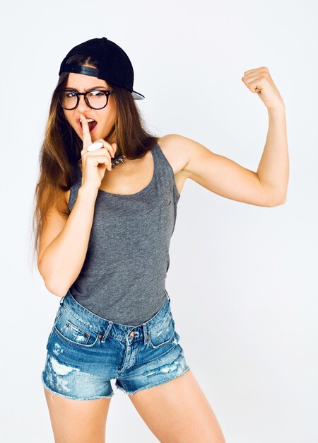 Lifestyle studio portrait of young cheeky pretty sportive girl having fun and showing her biceps