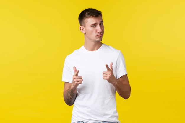 Lifestyle, summer and people emotions concept. Pleased and impressed handsome man congratulate you, look proud, pointing at camera saying well played, nice work, yellow background.