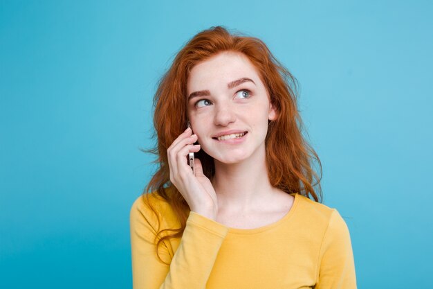 Концепция образа жизни и технологии - Портрет веселый счастливый рыжий рыжий волосы девушка с радостным и захватывающим разговором с другом по мобильному телефону. Изолированные на фоне голубой пастель. Копирование пространства.