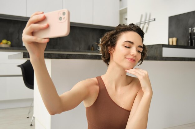 Lifestyle and workout modern fitness girl takes selfie on yoga mat does her exercises at home and ma