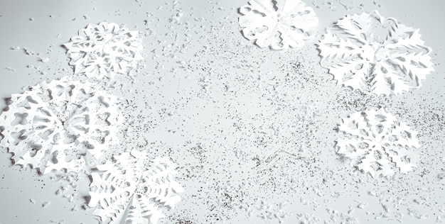 Light background with hand-cut paper snowflakes and sequins in a plane. christmas banner concept.