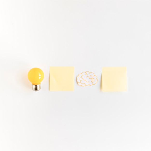Foto gratuita lampadina e cervello con due note adesive su sfondo bianco