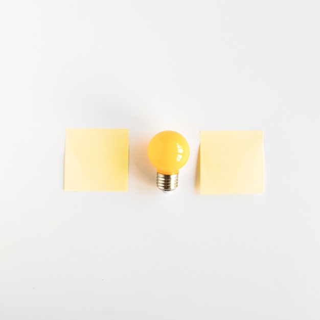 Light bulb between two adhesive notes on white background