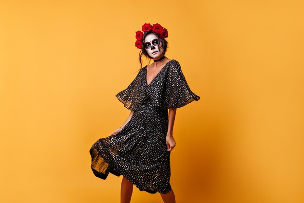 Light chiffon dress in polka dots scatters with every movement of amazing Latin woman in scary Halloween mask