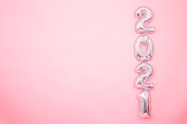 Светло-розовый фон с серебряными новогодними шарами в виде цифр справа, новогодняя концепция