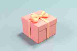 Free photo light pink gift box wrapped in yellow ribbon on a pale blue background