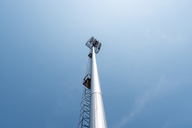 青い空のスポーツアリーナのライトポールタワー