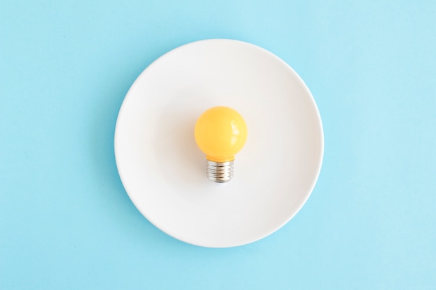 Light yellow bulb on white dish over the blue backdrop