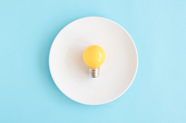 Light yellow bulb on white dish over the blue backdrop