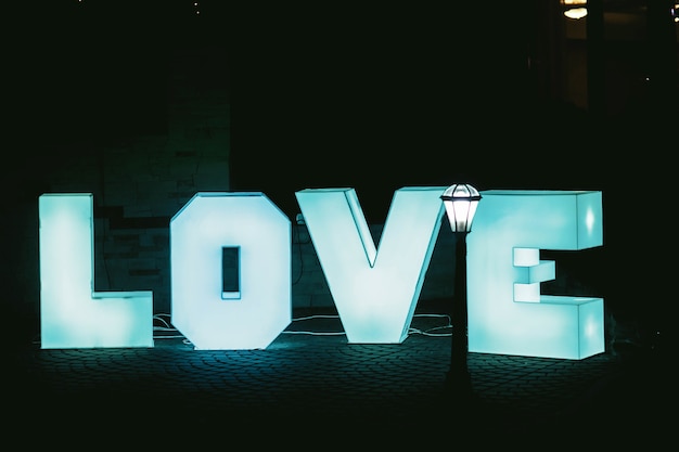 Free photo lighted big blue letters love with dark background