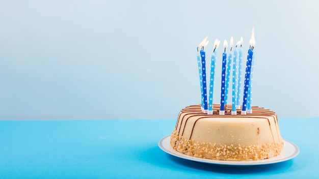 Lighted candles over the delicious cake against blue backdrop