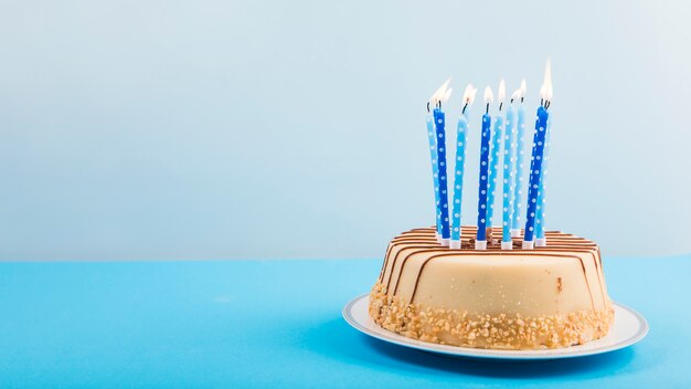 Зажженные свечи над вкусным тортом на голубом фоне