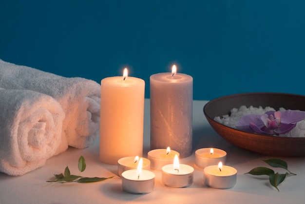 Lighted candles, rolled up towel and bath spa salt on table