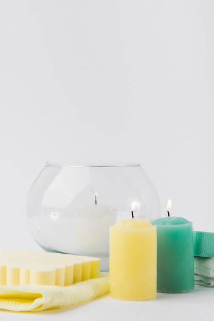 Free photo lighted colorful candles with sponge and napkin against white backdrop