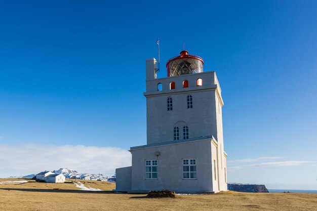 アイスランドの日光と青い空の下でディルホゥラエイの灯台