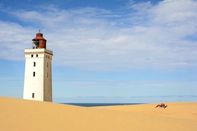 Lighthouse on the sand-covered beach on a sunny day