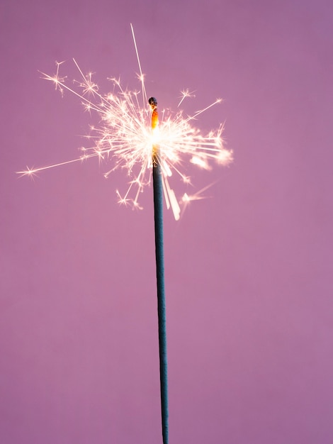 Foto gratuita sparkler di illuminazione su sfondo rosa