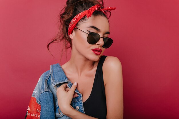 Lightly-tanned brunette girl in red ribbon and black glasses posing 