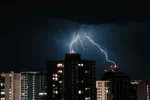 Free photo lightning in the dark sky over the buildings in the city at night