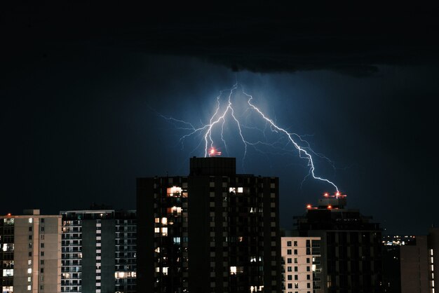 Молния в темном небе над зданиями в городе ночью