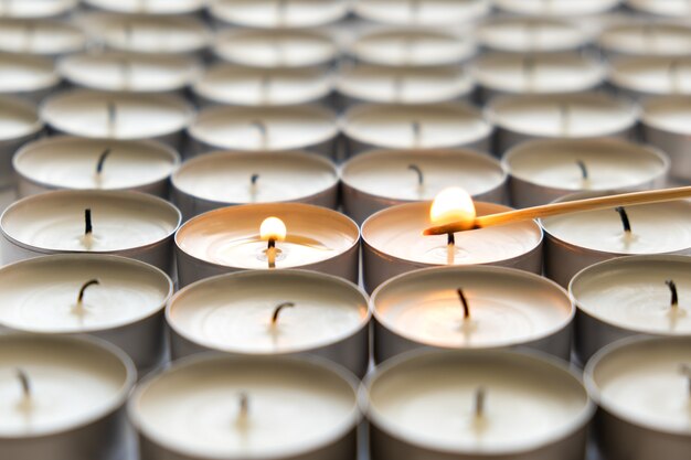 Lights many small round candles, close up.