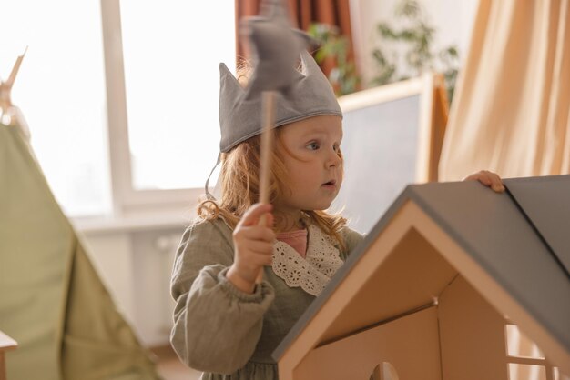 Lightskinned little girl with red hair wears toy crown magic wand with her indoors Baby concept