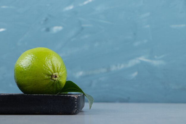 Lime fruit with leaves on cutting board. 