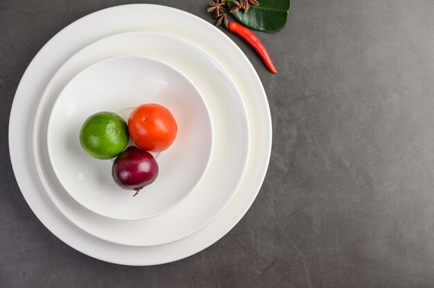 라임, 붉은 양파, 하얀 접시에 토마토.
