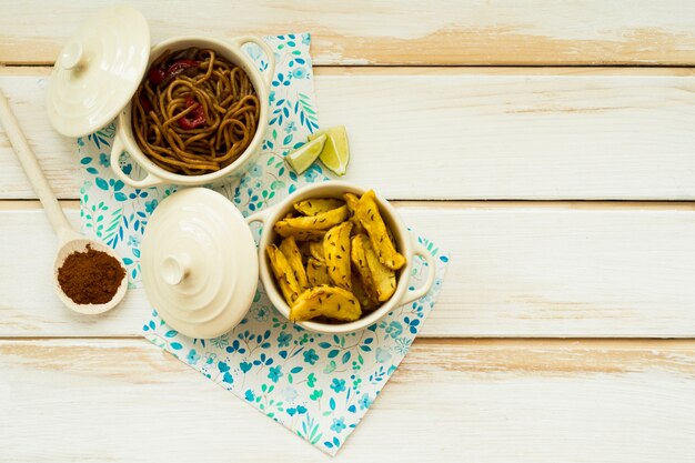 Lime and spices near pasta and fried potatoes