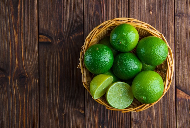 Free photo limes in a wicker basket on wooden table. flat lay.