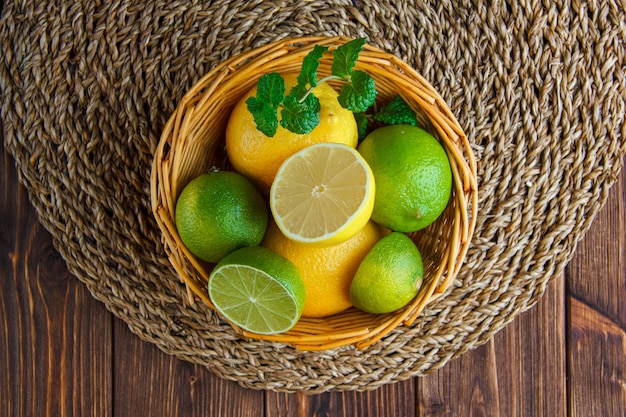 Limes with lemons, herbs in a wicker basket on wooden table